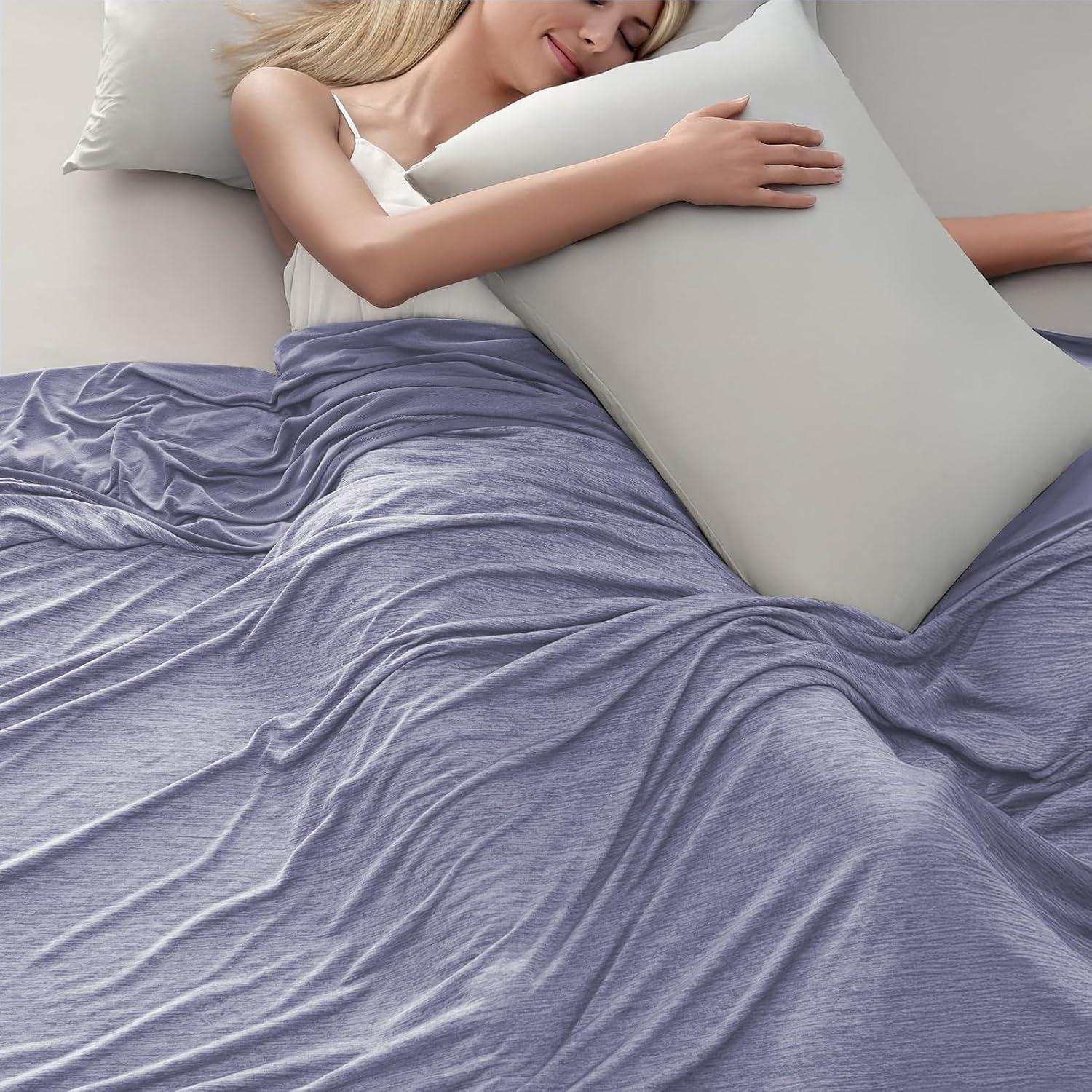 The Arc-Chill cooling blanket in Lavender Grey spread across a bed, with a woman asleep under it